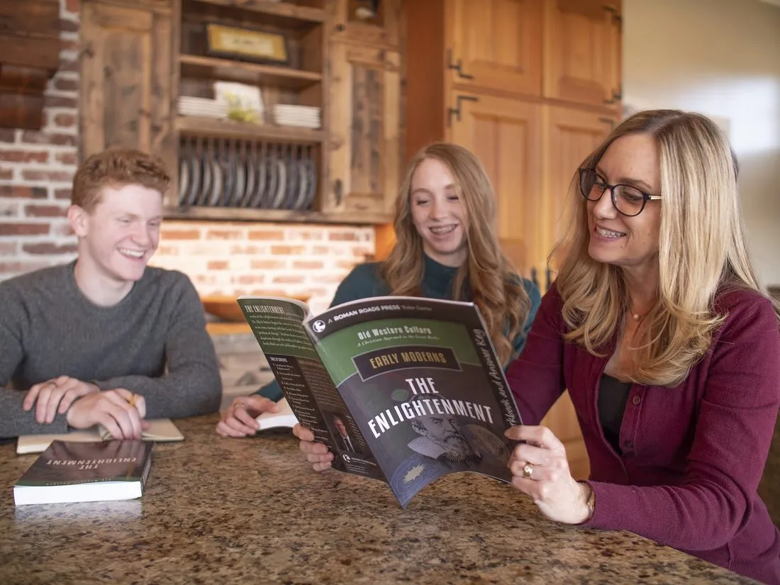 A mother and two teenagers reading an Old Western Culture workbook together at the kitchen counter